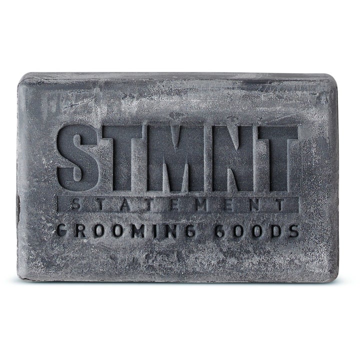 STMNT Grooming Goods Hair & Body Soapbar 125 g rengjørende såpestykke i mørkegrå farge med grov tekstur og logo