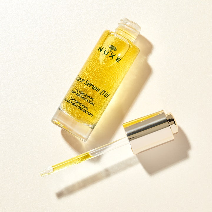 Nuxe Super Serum 30 ml anti-age serum i glassflaske med pipette som viser gylne oljeperler for glød