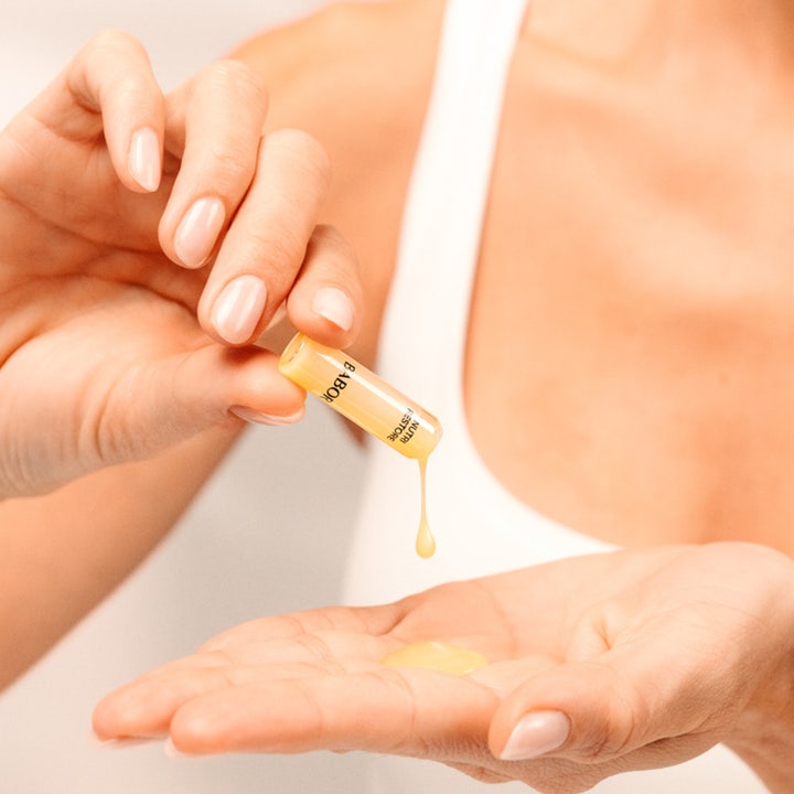 Babor Nutri Restore Ampoule 14 ml næringsgivende serum for ansiktsvård i en glassampulle som holdes av hender.