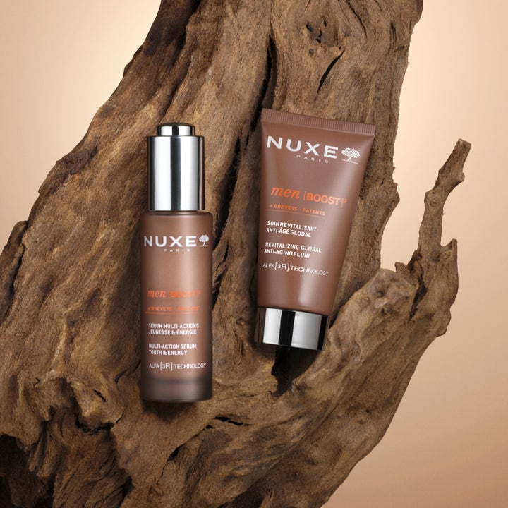 Nuxe Men Anti Age Cream 50 ml revitaliserende dagkrem i brune beholdere med sølvdetaljer på en rustikk trebakgrunn.