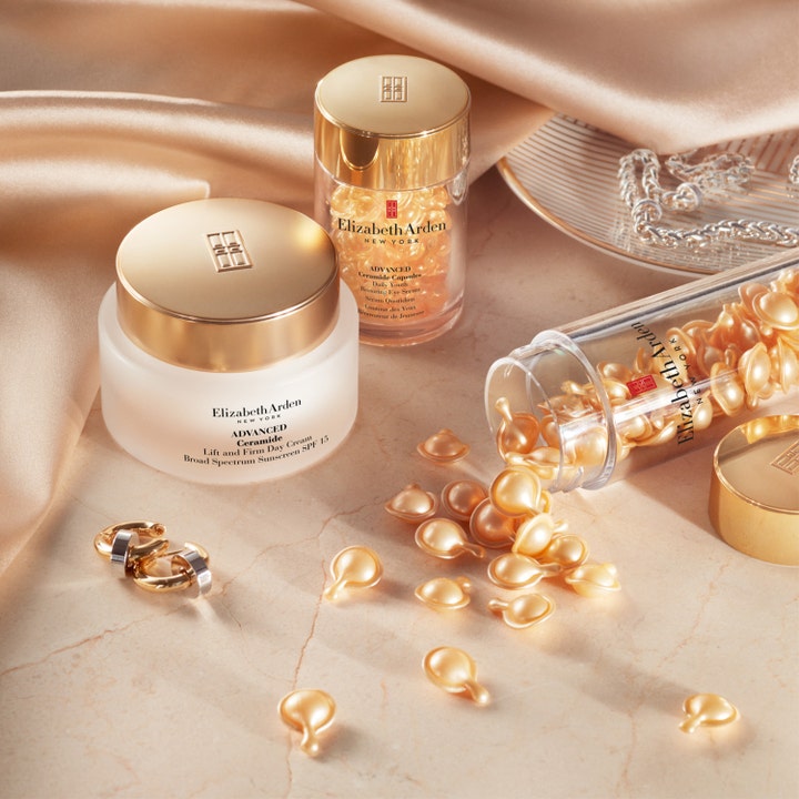 Elizabeth Arden Advanced Ceramide 30 stk gjenoppbyggende serum med gylne kapsler spredt utover marmor.