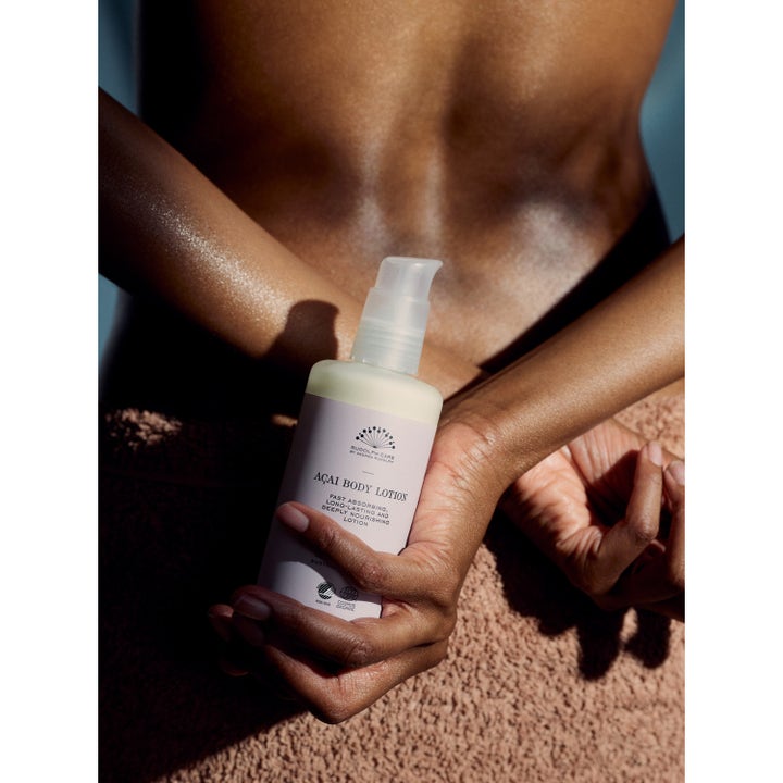 Rudolph Care Açai Body Lotion 200 ml fuktighetsgivende bodylotion i pumpeflaske holdt mot bar hud som har fått glød