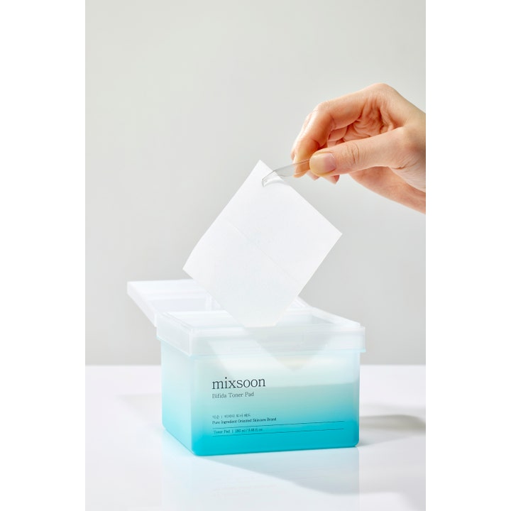 Mixsoon Bifida Toner Pad 120 stk styrkende ansiktsmaske i blå boks der en hvit pad løftes ut med pinsett.