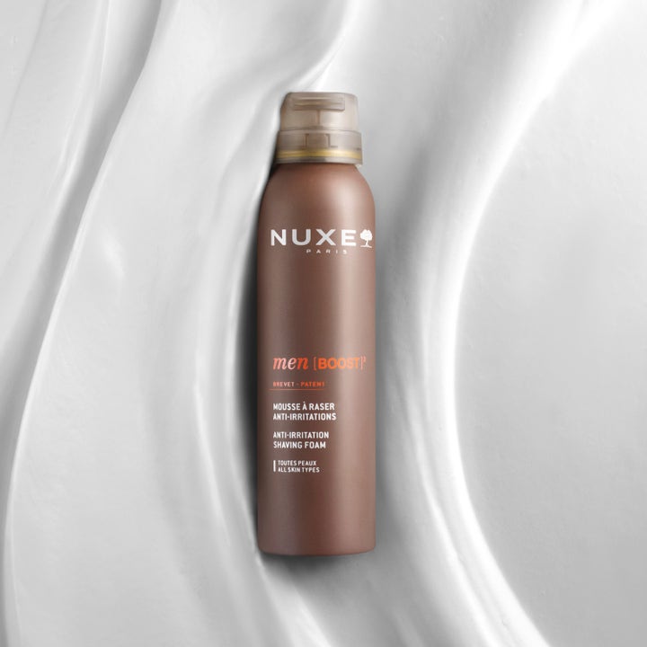 Nuxe Men Shaving Foam 150 ml anti-irritasjon barberingsskum i brun boks på hvit, bølget og kremet bakgrunn.
