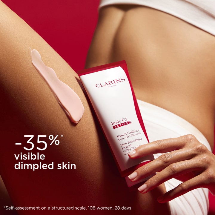 Clarins Body Fit Active 200 ml utglattende kroppskrem med rosa tekstur på lår og rød tube med tekst om mindre ujevn hud