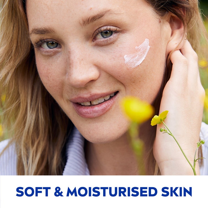 NIVEA Soft 75 ml fuktighetskrem som gir myk hud vist på kinnet til en smilende kvinne utendørs