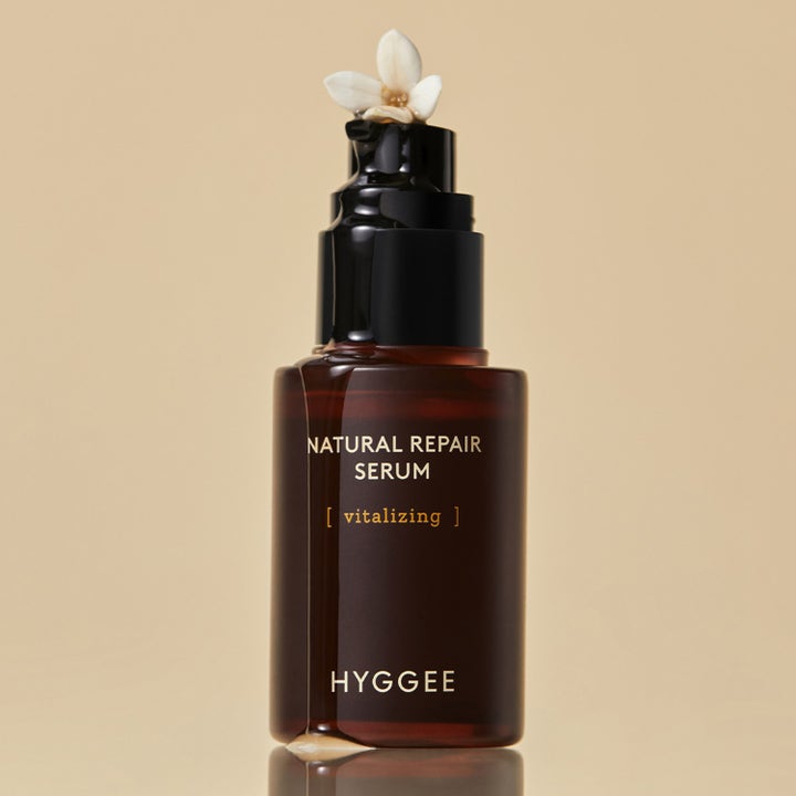Hyggee Natural Repair Serum 30 ml vitaliserende ansiktsserum i brun glassflaske med hvit blomst og flytende dråpe.