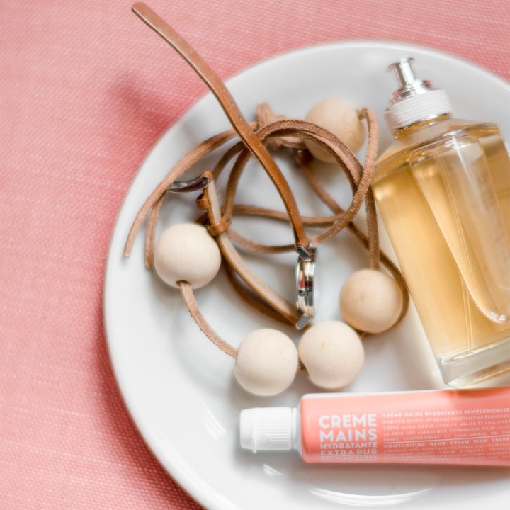 Compagnie de Provence Hand Cream Pink Grapefruit 30 ml fuktighetsgivende håndkrem i rosa tube på hvit tallerken med perler.