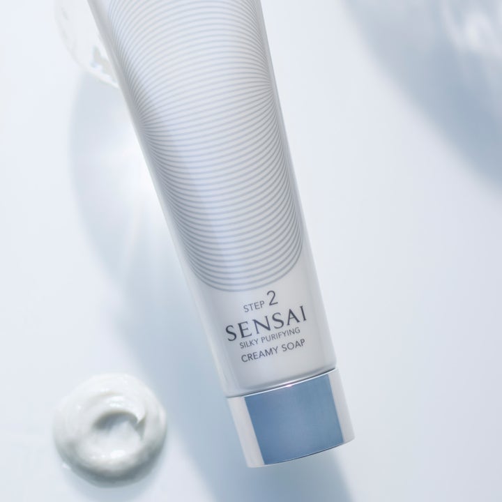 Sensai Silky Purifying Creamy Soap N 125 ml ansiktsrengjøring i hvit tube med sølvkork og kremet teksturprøve.