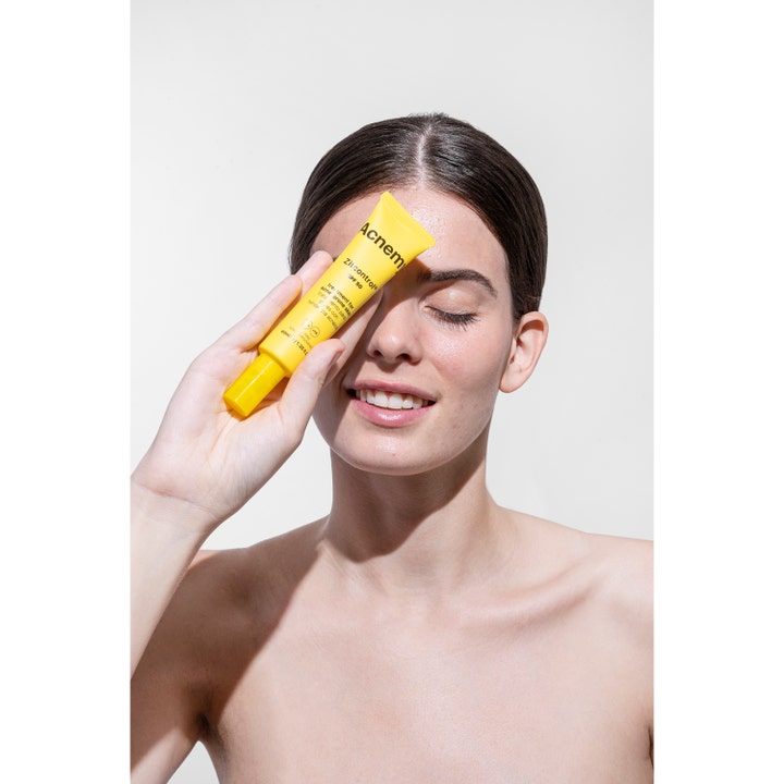 Niche Beauty Lab Acnemy Zitcontrol SPF 50 40 ml dagkrem i gul tube holdt av smilende kvinne