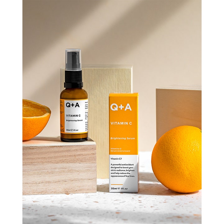 Q+A Vitamin C Brightening Serum 30 ml glødgivende hudpleie i amber glassflaske ved siden av friske appelsiner.