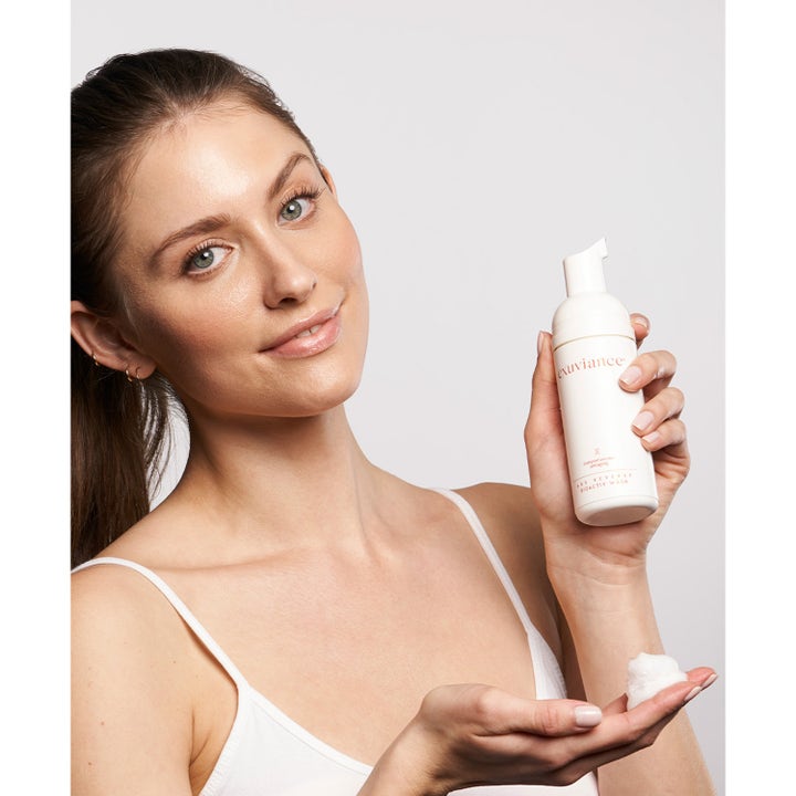 Exuviance Age Reverse BioActiv Wash 125 ml ansiktsrens kvinne holder hvit pumpeflaske med fyldig renseskum