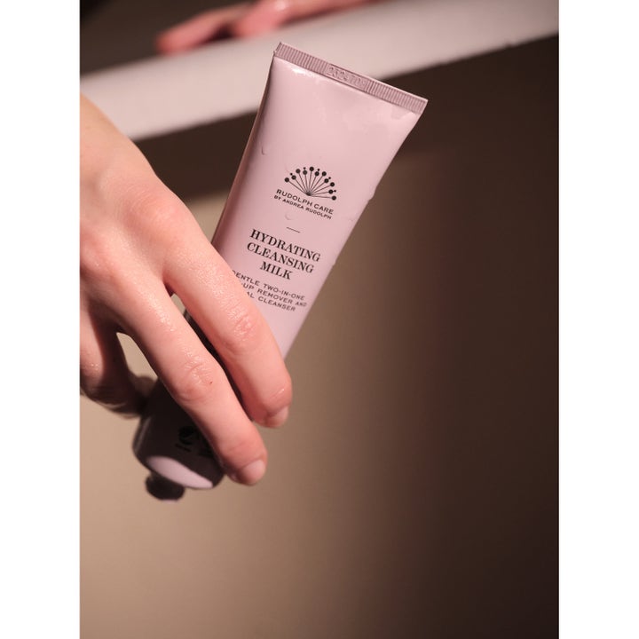 Rudolph Care Acai Hydrating Cleansing Milk 100 ml fuktighetsgivende ansiktsrens i lyserosa tube holdt av en hånd