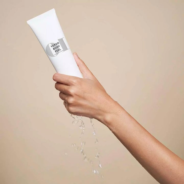 Verso N°10 Body Peel 150 ml eksfolierende kroppsskrubb med AHA og BHA i hvit tube holdt av hånd med vanndråper