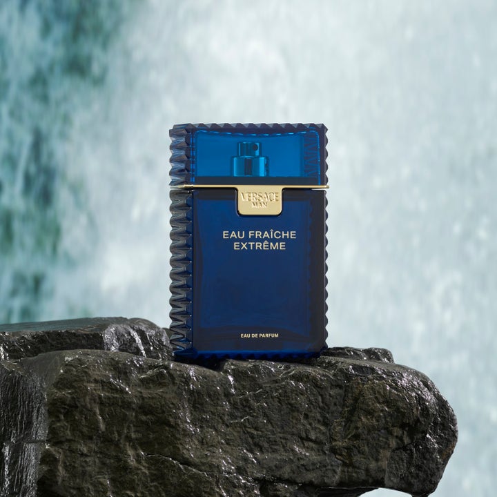 Versace Eau Fraiche Extreme Deodorant Stick 75 ml herredeodorant i blå flakong plassert på en våt stein foran en foss.