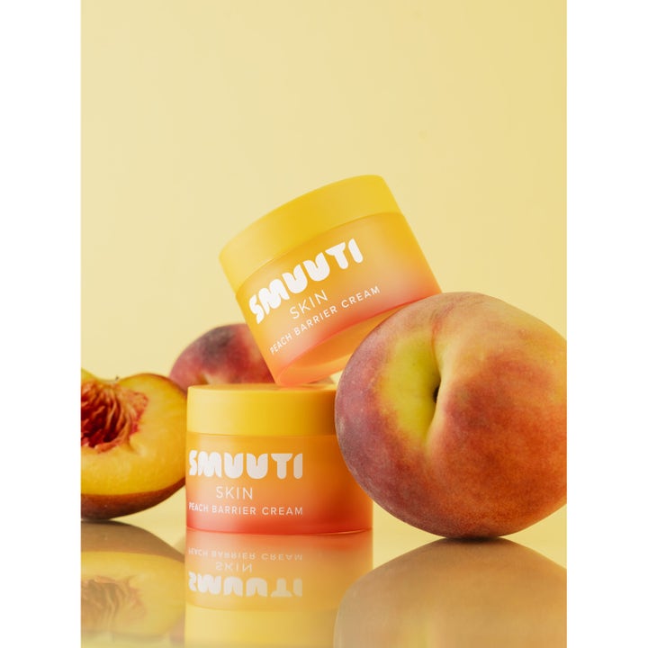 Smuuti Skin Peach Barrier Cream 50 ml fuktighetskrem i oransje krukker ved siden av friske fersken.