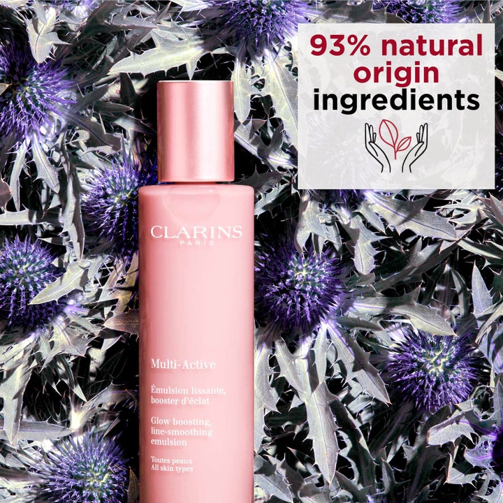 Clarins Multi-Active Emulsion 100 ml glødgivende ansiktskrem i rosa flaske blant lilla tistler med 93% naturlig opprinnelse