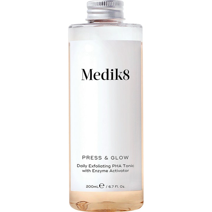 Medik8 Press & Glow 200 ml eksfolierende toner gir glød i klar flaske med sølvfarget kork og ferskenfarget væske.