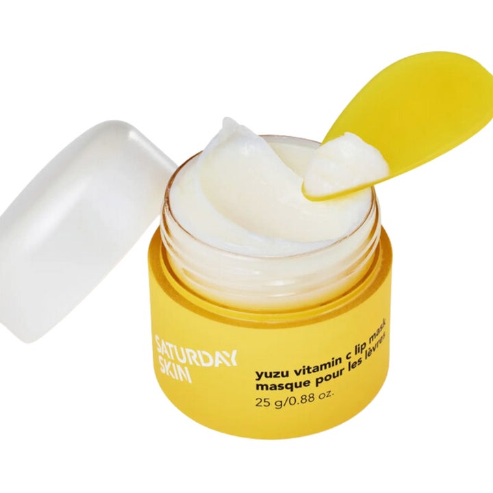 Saturday Skin Yuzu Vitamin C Lip Mask 25 g gir fuktighet i gul krukke med hvit kremaktig tekstur og spatel