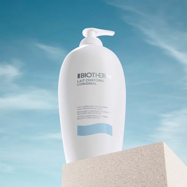 Biotherm Lait Corporel 400 ml fuktighetsgivende kroppslotion i hvit pumpeflaske på sten mot blå himmel