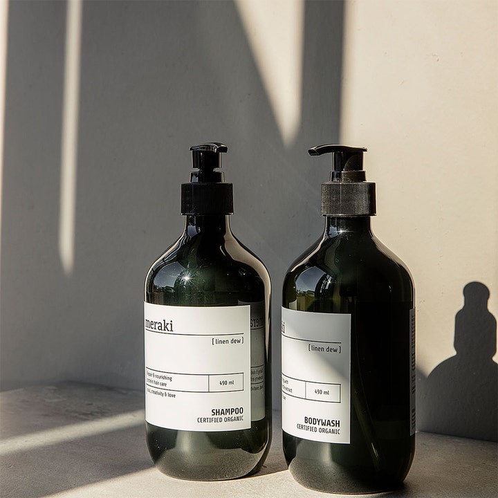 Meraki Linen Dew Body Wash 490 ml pleiende dusjsåpe i mørkegrønn pumpeflaske ved siden av matchende sjampo