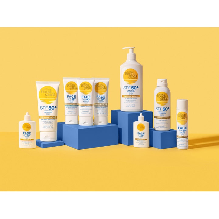 Bondi Sands SPF50+ Everyday Aerosol Mist Spray 160 g solkrem i hvit flaske på blå podier mot gul bakgrunn.