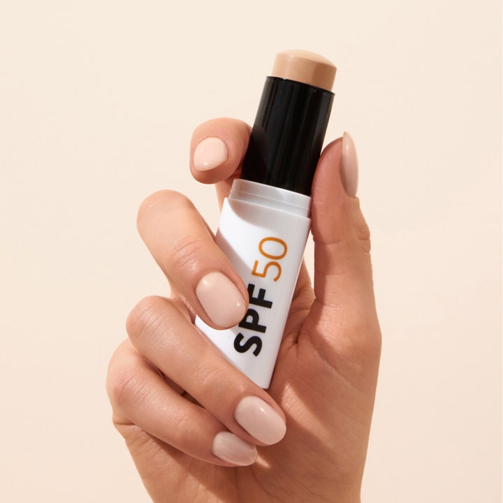 MÁDARA Mineral SPF50 Sunscreen Stick 12 g beskyttende solkrem i hvit stift som holdes av en hånd mot en beige bakgrunn