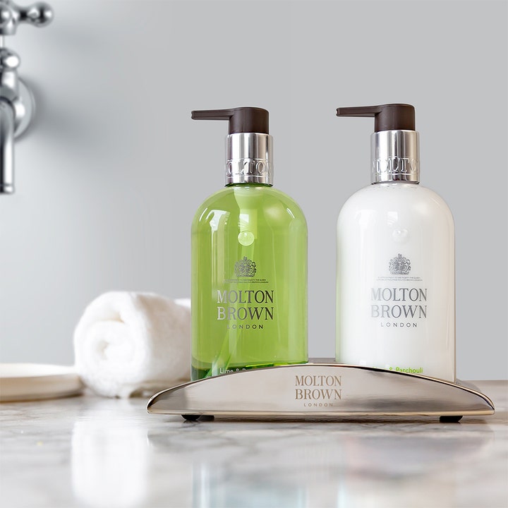 Molton Brown Lime & Patchouli Hand Lotion 300 ml pleiende handvård i hvit pumpeflaske i sølvholder på marmor