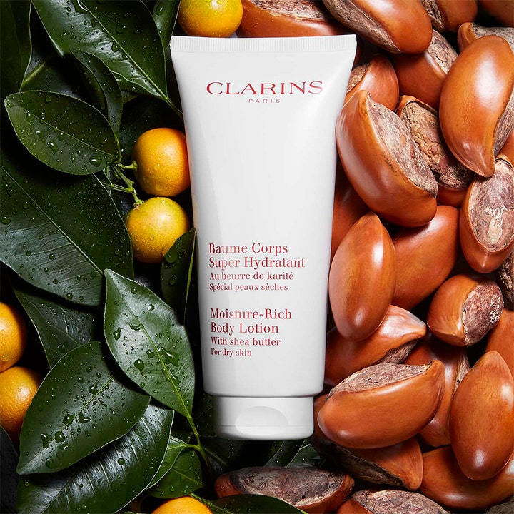 Clarins Moisture-Rich Body Lotion 200 ml fuktighetskrem på tube omgitt av sheanøtter og grønne blader