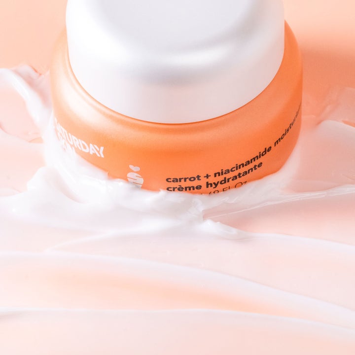 Saturday Skin Carrot + Niacinamide Moisturizing Cream 50 ml i oransje krukke omgitt av hvit, kremet tekstur.