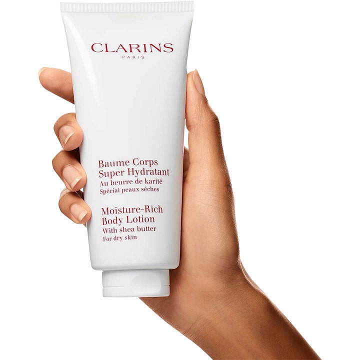Clarins Moisture-Rich Body Lotion 200 ml fuktighetsgivende bodylotion for tørr hud i hvit tube holdt av en hånd